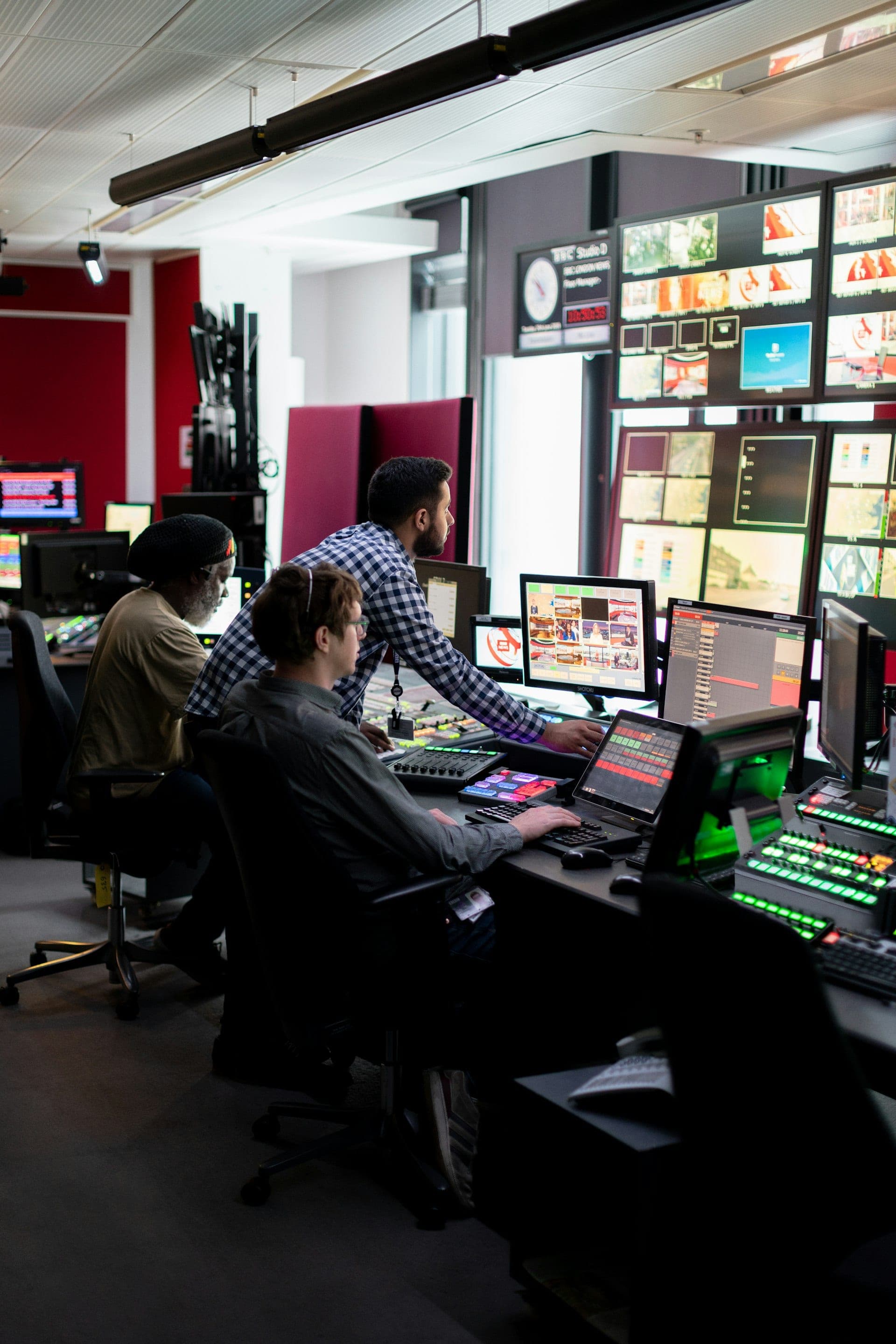 Technicians at a control desk lined with monitors and instrument readouts.